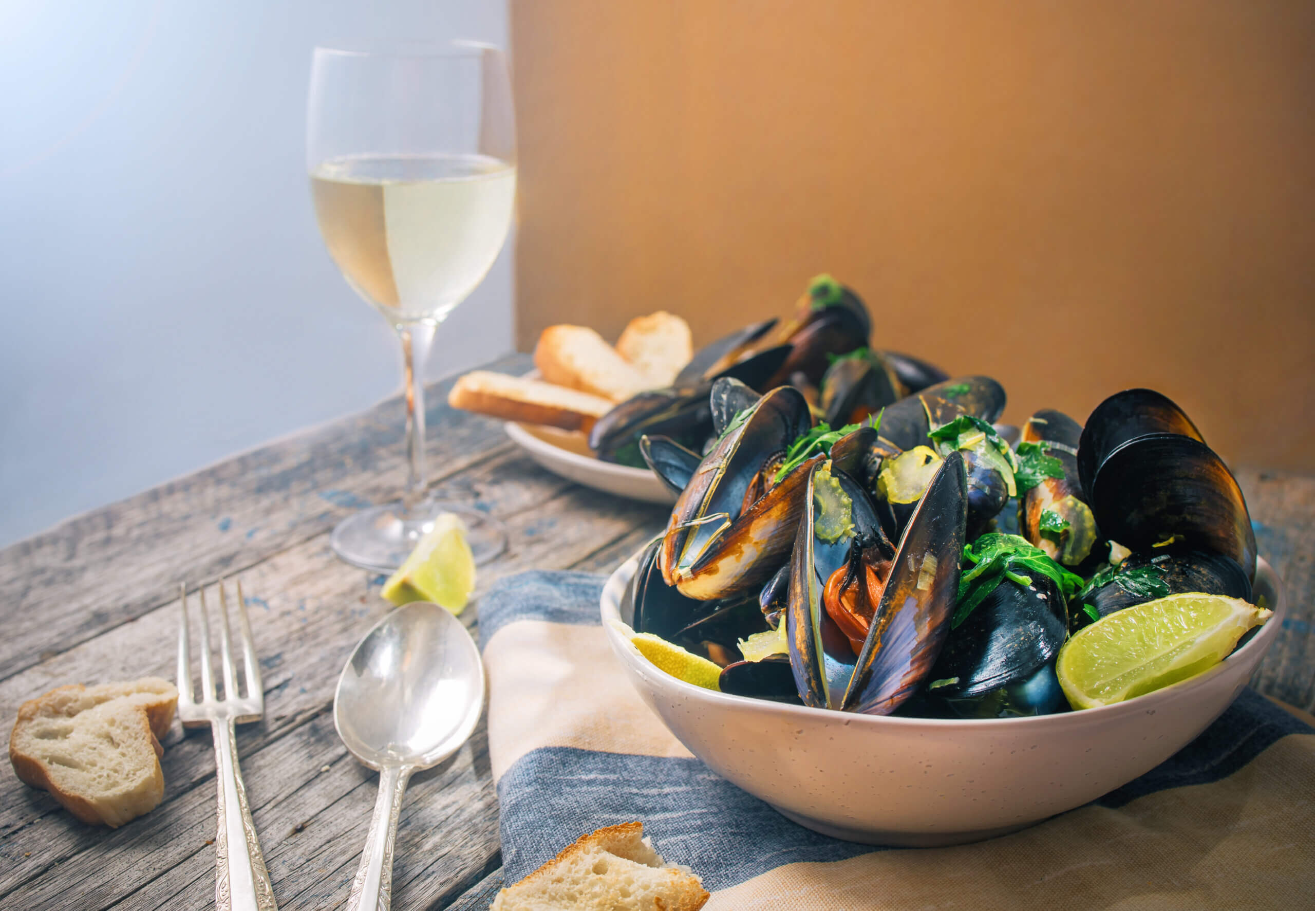 Cooking with Wine using Rolling Forks Vineyards fine wines. Blue mussles with vine and baguette on wooden table with sunlight