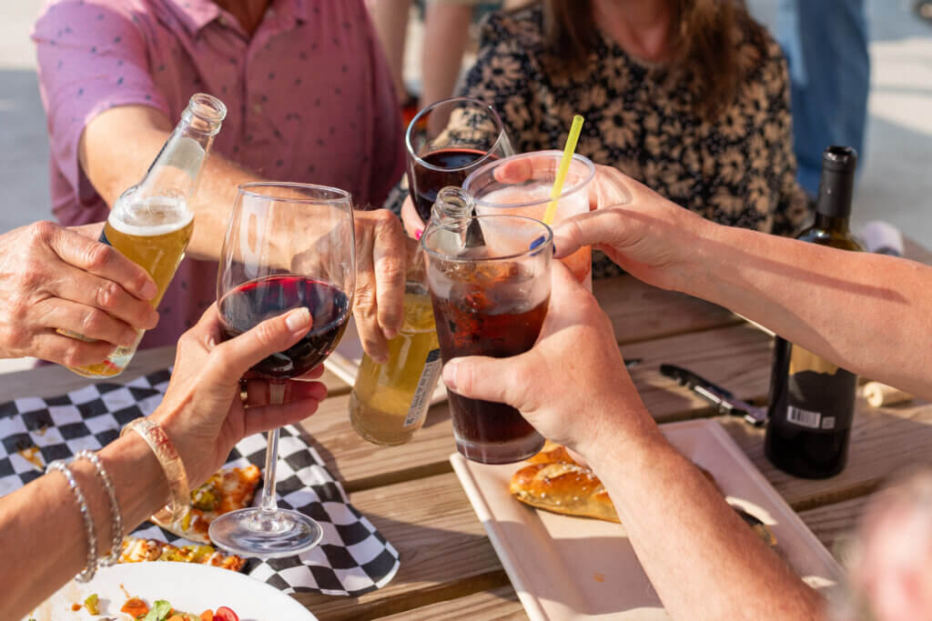 Group of friends toast at Rolling Forks Vineyards enjoying food and wine on the patio