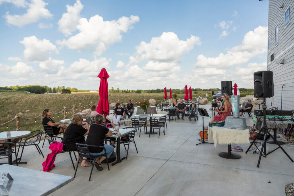 Acoustic guitarist performing live music at Rolling Forks VIneyards patio in Glenwood during a weekend wine tasting event enjoying the scenic vineyard views and outdoor seating area for live music events