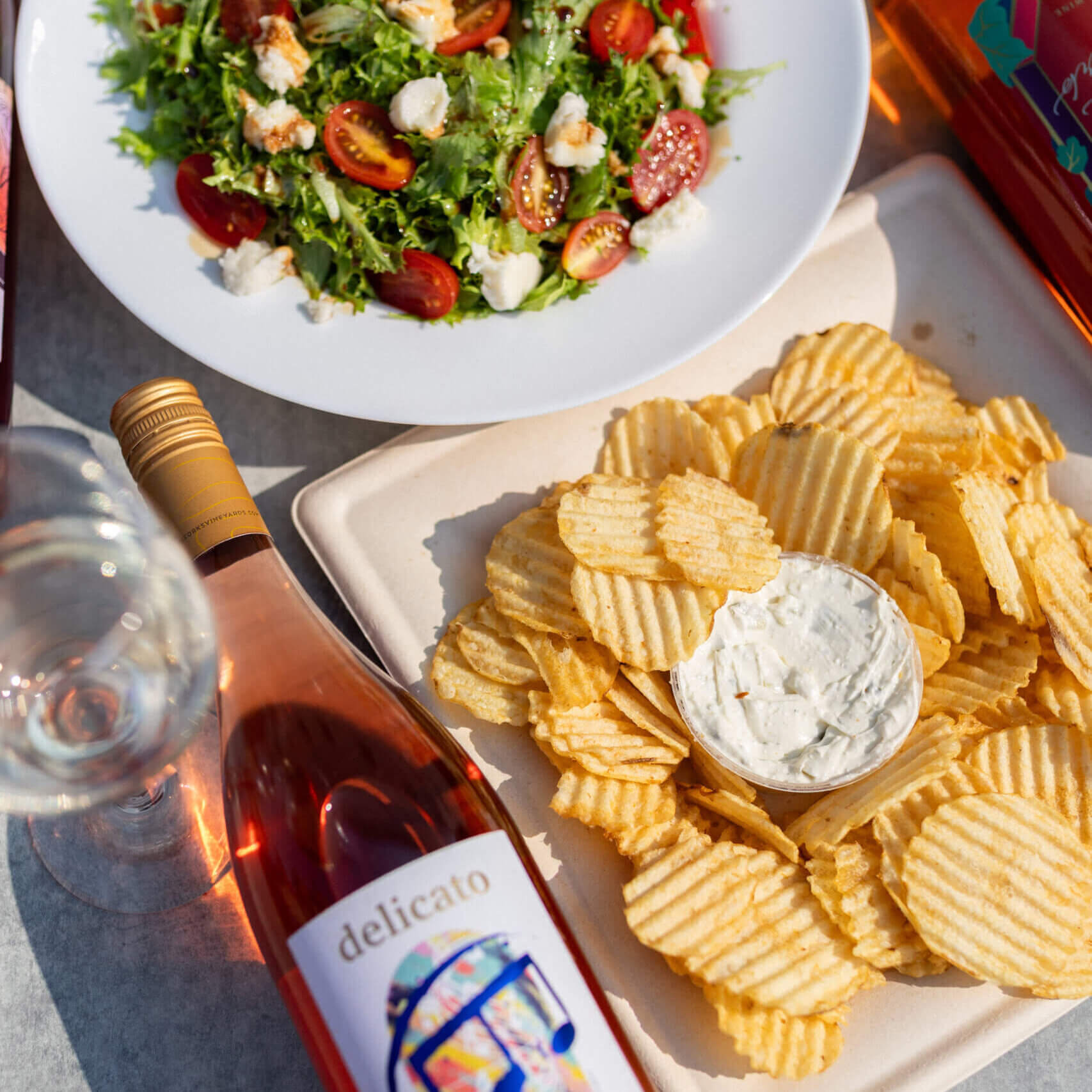 Delicato rose' wine by Rolling Forks Vineyards shown with crunchy potato chips with fresh dill dip and a beautiful summer salad enjoyed on the patio overlooking Lake Minnewasaka in Glenwood, Minnesota.