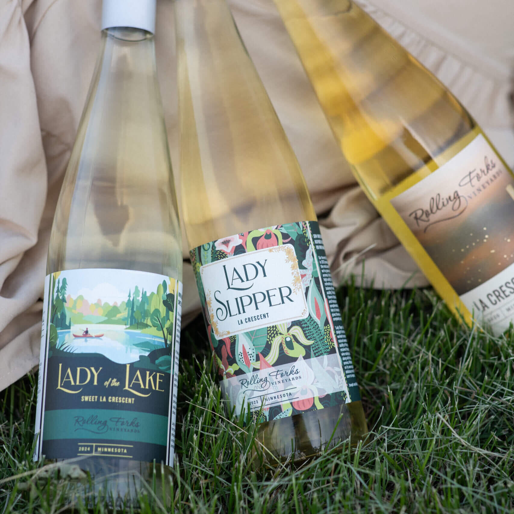 Lady of the Lake: A bottle of 2024 Lady of the Lake La Crescent, a sweet white wine from Rolling Forks Vineyards, featuring its Best of Class medal from the San Francisco Chronicle Wine Competition. Lady Slipper: A bottle of Rolling Forks Vineyards Lady Slipper, an off-sweet La Crescent white wine, showcasing its Double Gold medal.