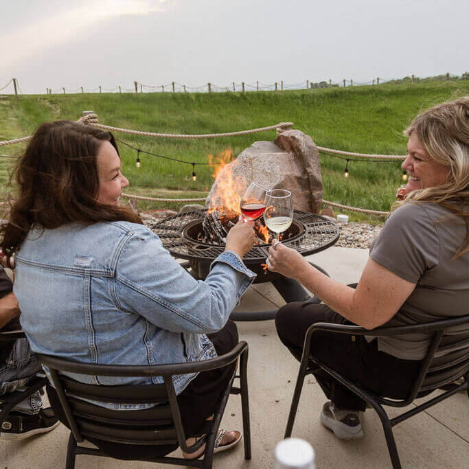 Friends around the fire toasting with Rolling Forks Vineyards wines on a summer evening